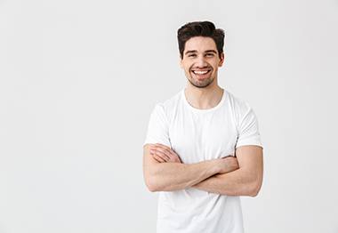 Young man in white shirt enjoying benefits of dental crowns