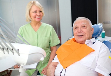 An older patient sitting with a dental employee.
