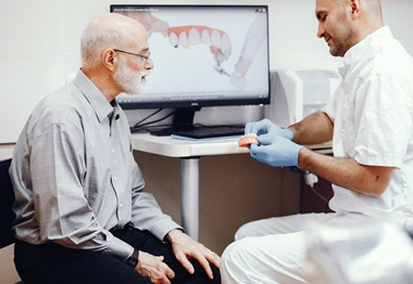 A dentist explaining denture care to a patient.