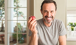 Older bearded man holding an apple