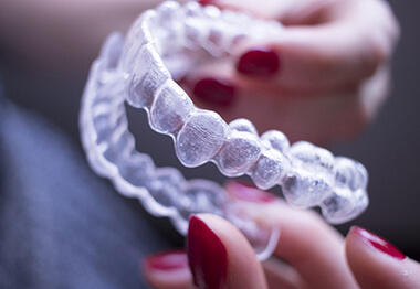 Woman’s hands holding a pair of Invisalign aligners