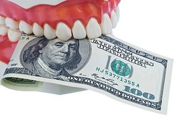 Teeth biting money representing an expense. 