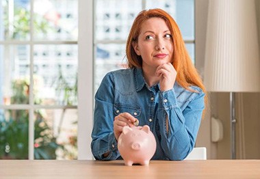 woman and piggy bank for cost of teeth whitening Hoboken