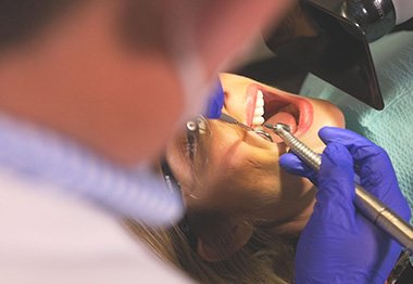 Dentist treating dental patient wearing personal protective equipment